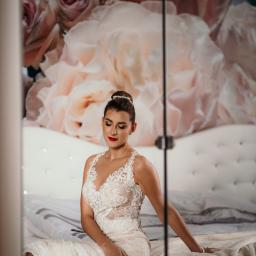 ACfotografia fotografia ślubna Gdańsk Trójmiasto - Panna młoda w koronkowej sukni siedzi na łóżku z kwiatowym tłem, z zamkniętymi oczami i czerwonymi ustami.