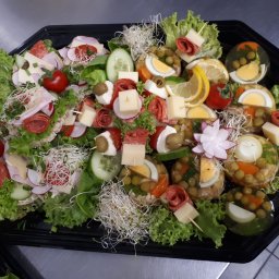 AgawaHouse - Elegancka taca cateringowa z galaretkami, koreczkami i kanapkami na sałacie, udekorowana rzodkiewką i kiełkami, prezentowana na metalowym stole.