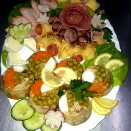 AgawaHouse - Elegancka kompozycja galaretek z groszkiem, mięs, serów i warzyw na białym talerzu, dekorowana sałatą i cytryną. Idealna na catering świąteczny.