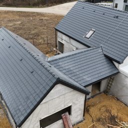 Ostafiński Mariusz Usługi Dekarsko - Ciesielsko - Blacharskie - Nowoczesny dom w trakcie budowy z grafitowym dachem z dachówki ceramicznej. Widok z góry ukazuje postęp prac i detale wykończenia.