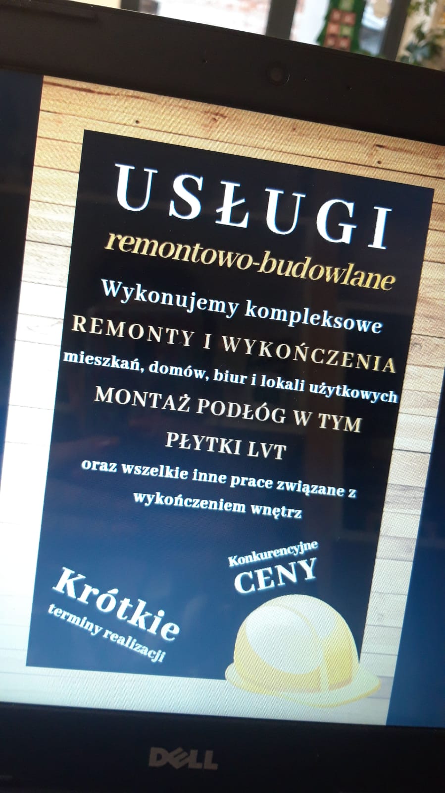 Zdjęcie ekranu laptopa Dell prezentującego plakat reklamowy usług remontowo-budowlanych, w tym montażu podłóg i płytek LVT, z zapewnieniem o krótkich terminach realizacji i konkurencyjnych cenach.