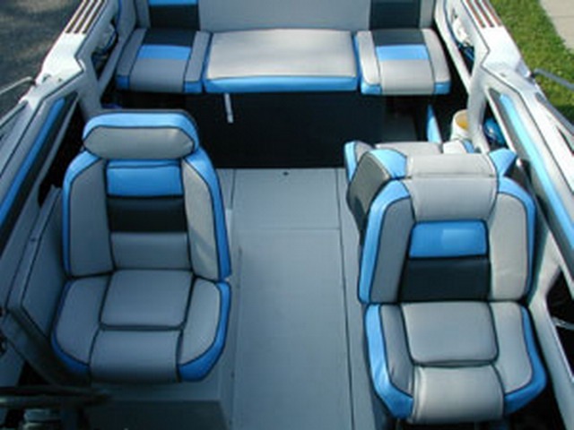 Wnętrze łodzi motorowej z nową, jasnoszarą tapicerką z akcentami czerni i błękitu na fotelach i kanapach.