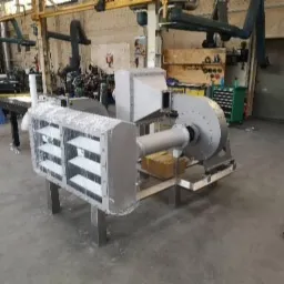 Element instalacji przemysłowej ze stali nierdzewnej, prawdopodobnie wentylacyjnej, z kratką i wentylatorem, na tle hali produkcyjnej.