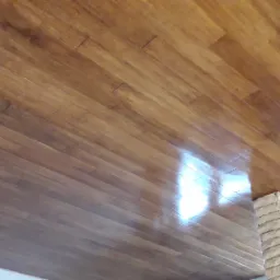 Świeżo ułożony parkiet z egzotycznego drewna, widoczny fragment kamiennej dekoracji ściany w surowym stanie.