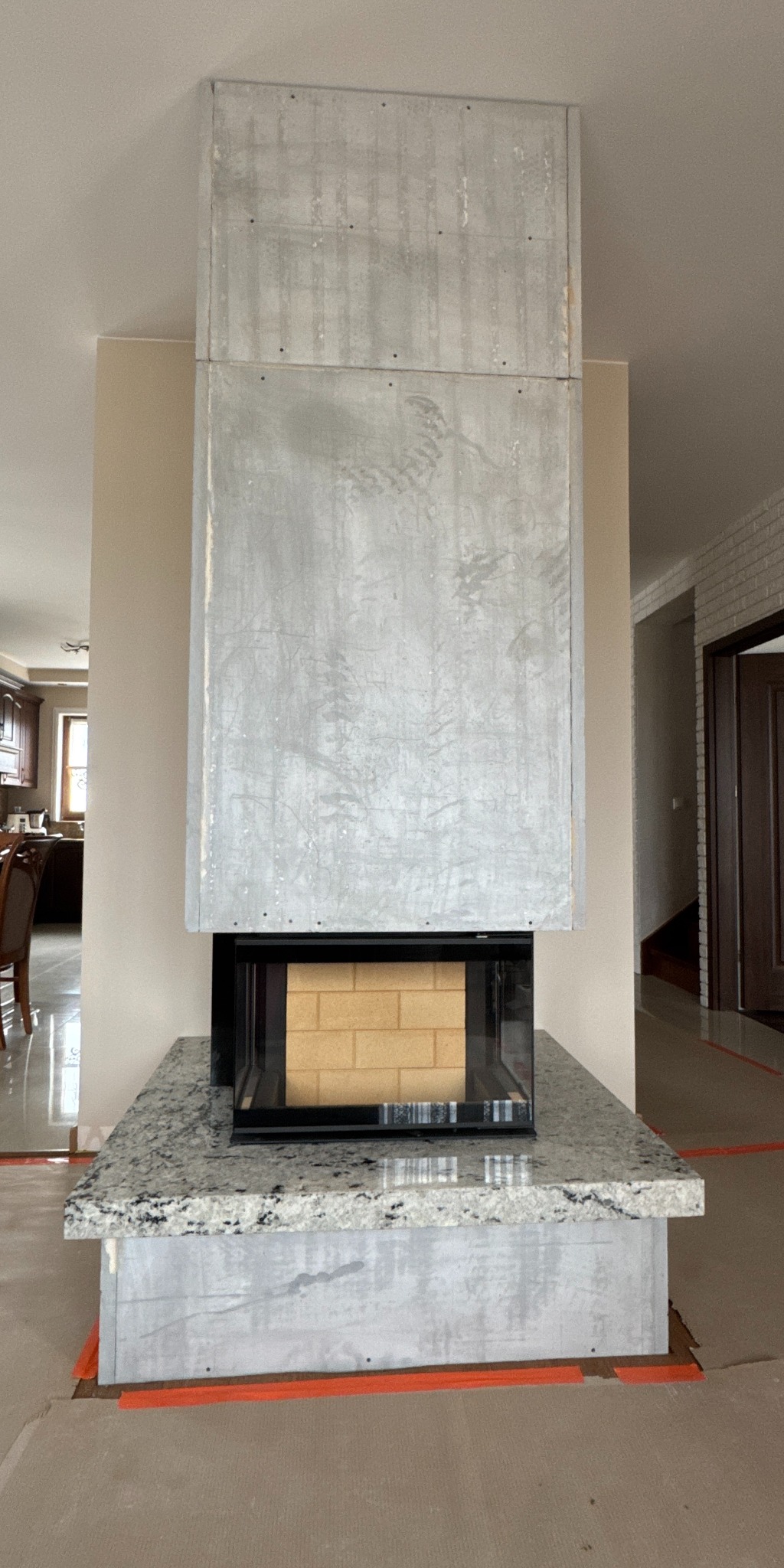 Nowoczesny kominek z obudową z betonu architektonicznego i blatem z granitu, widok z przodu, wnętrze domu.