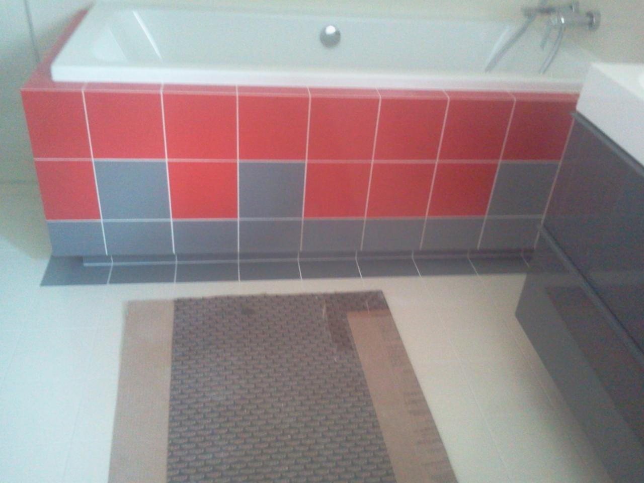 Wykończona obudowa wanny z czerwono-szarymi płytkami, widoczny fragment podłogi i szafki łazienkowej w nowoczesnej aranżacji.