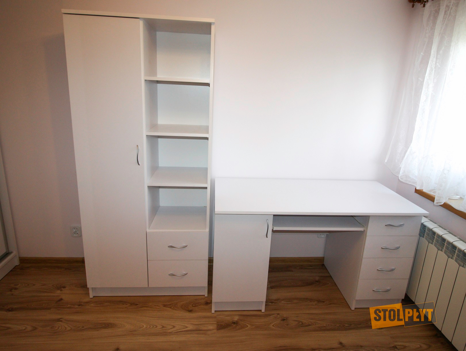 Biały zestaw mebli: szafa z półkami i biurko z szufladami, widoczne na tle jasnej ściany i drewnianej podłogi.