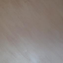 Krzysztof - Świeżo pomalowana ściana w odcieniach beżu z widoczną strukturą farby i delikatnymi smugami, ukazująca efekt dekoracyjny.