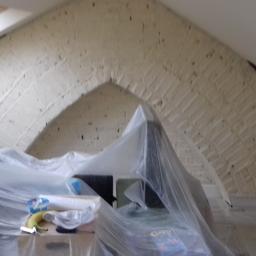 Krzysztof - Poddasze z ceglanym łukiem, zabezpieczone folią malarską, widoczne materiały i narzędzia malarskie, banan jako przekąska.