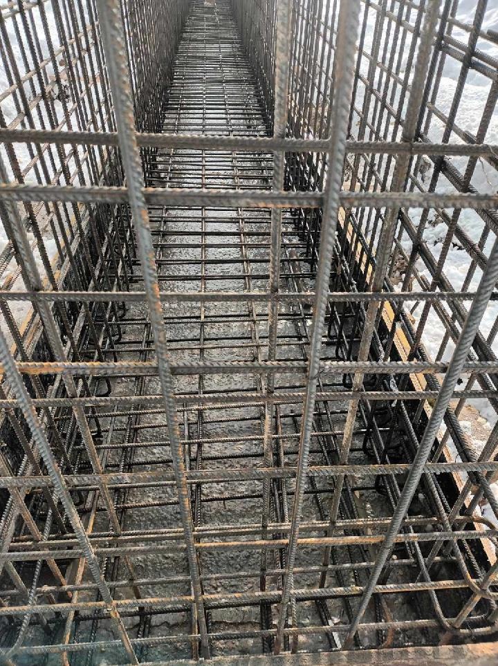 Metalowe zbrojenie ułożone w wykopie, przygotowane do zalania betonem, widok z góry.