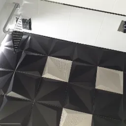 Nowoczesna łazienka z czarno-białymi trójwymiarowymi płytkami, deszczownicą i minimalistyczną armaturą.