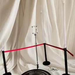 Okrągła platforma 360 z napisem '360 PHOTOBOOTH' i logo 'FBUDKI.PL', otoczona czarnymi słupkami z białymi lampami i czerwoną taśmą na tle białej, drapowanej tkaniny.