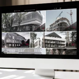 Monitor iMac wyświetlający galerię zdjęć nowoczesnych budynków, w tym budynek medyczny i budowę z dźwigiem, na stronie internetowej z logo Spectrum.