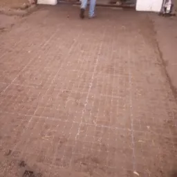 Przygotowany teren pod ułożenie nawierzchni z widoczną siatką podziału, osoba oddalająca się w kierunku garażu.