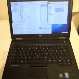 Otwarty laptop Dell Latitude E5440 z uruchomionym systemem Windows 10 i otwartymi oknami programu, widoczne naklejki Windows 7 i Intel Core i5.