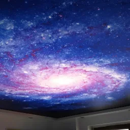 Sufit napinany z nadrukiem galaktyki spiralnej w odcieniach niebieskiego i różowego, widoczne halogenowe punkty oświetleniowe.