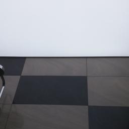 Rinam - Nowoczesny prysznic z chromowaną deszczownicą, czarno-szare kwadratowe płytki na ścianie i podświetlany sufit napinany.