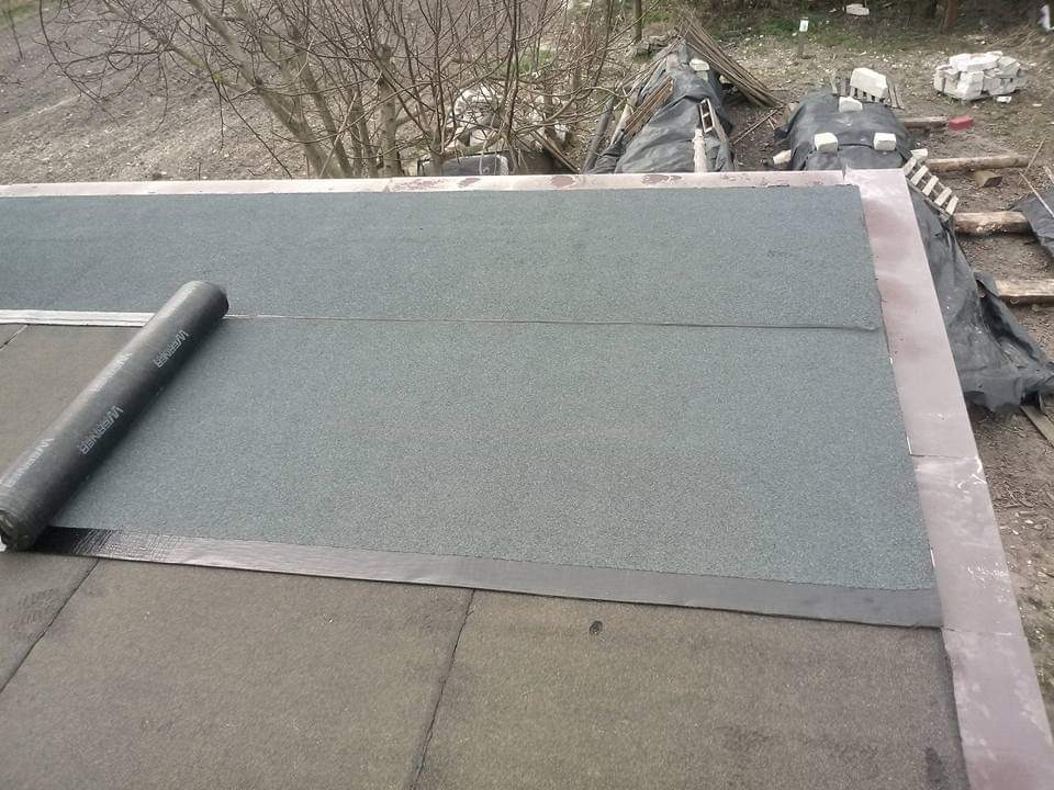 Układanie papy termozgrzewalnej na dachu, widoczny częściowo rozwinięty wałek papy firmy Werner.