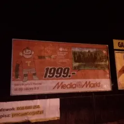Billboard reklamowy Media Markt prezentujący telewizor LG 55 cali w cenie 1999 zł, obok inny billboard z kobietą w stroju Mikołajki.