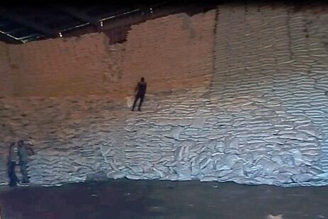 Magazyn wypełniony workami z cukrem ICUMSA 45, widoczni pracownicy przy układaniu worków.