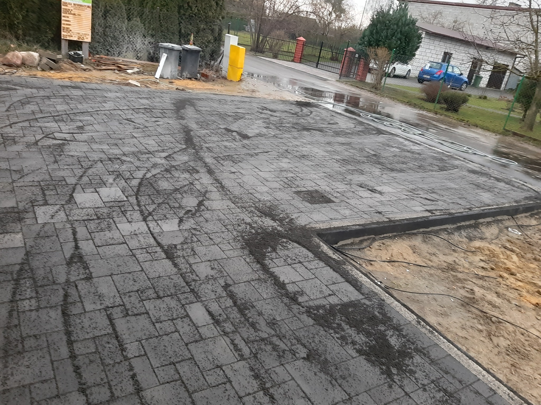 Układanie kostki brukowej w Borowie, widoczne ślady po oponach na świeżo ułożonej nawierzchni z szarej kostki, obok przygotowane podłoże pod dalszą część chodnika.