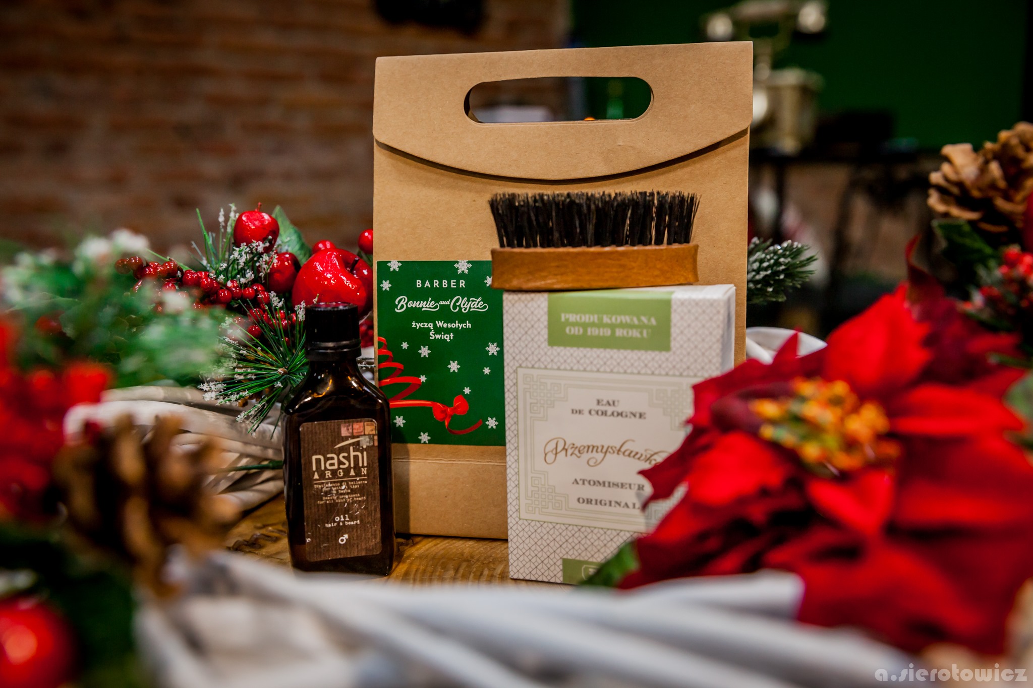 Zestaw prezentowy dla mężczyzny z olejkiem do brody, pędzlem do golenia i wodą kolońską, umieszczony na drewnianym stole z dekoracjami świątecznymi