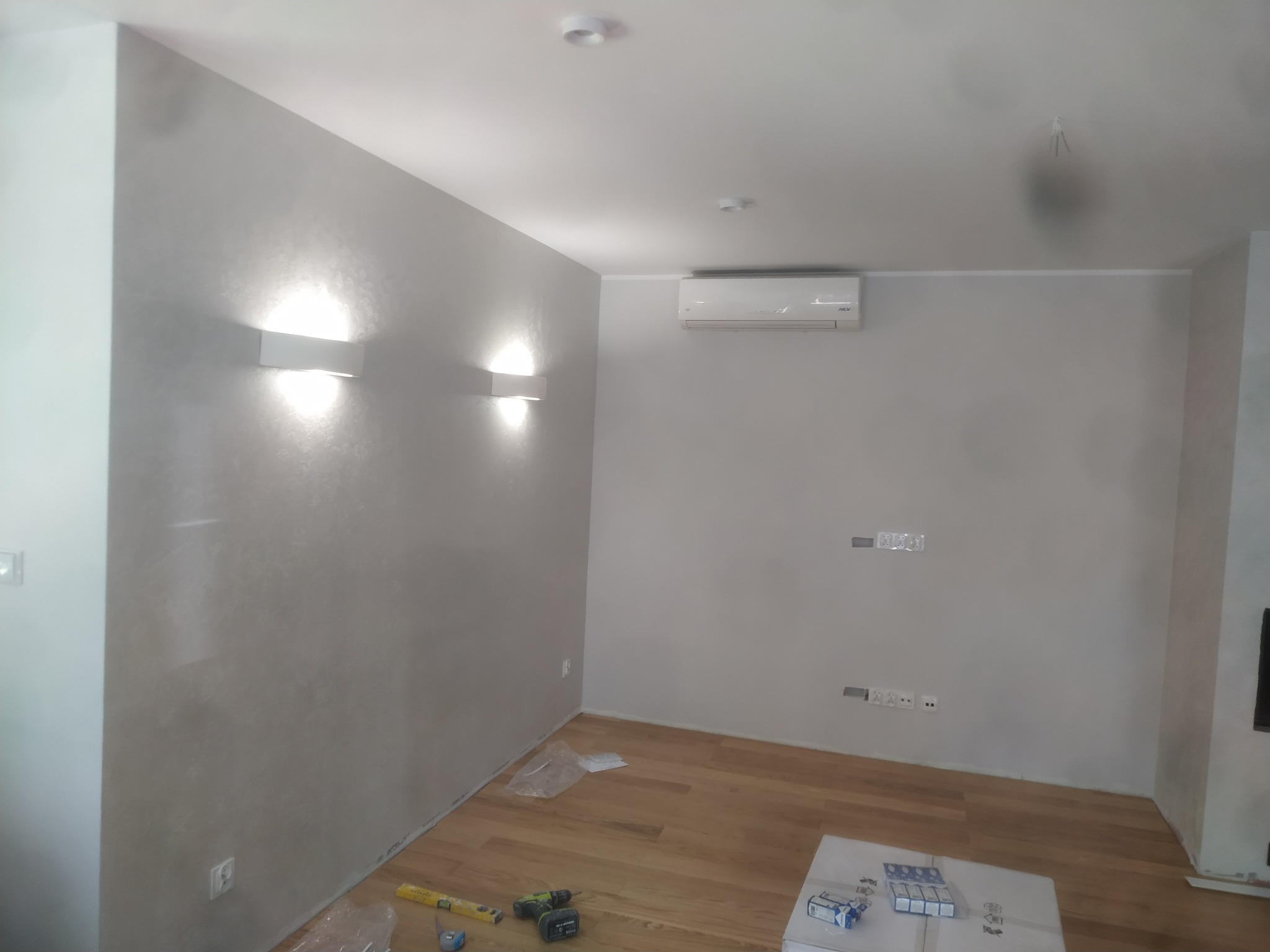 Pokój po odświeżeniu ścian z zamontowanym klimatyzatorem, widoczne narzędzia i materiały na podłodze