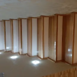 Nowoczesne schody z drewnianymi balustradami i białymi panelami, oświetlone punktowymi lampami w podłodze.