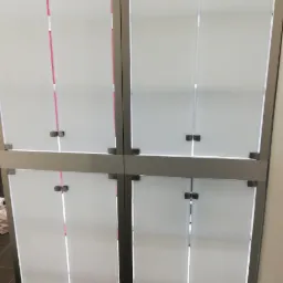 Szklana gablota z metalowymi ramami i uchwytami, widok z bliska na zamknięte drzwi.