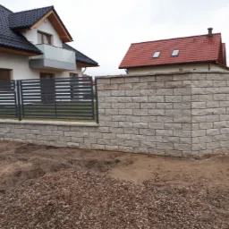Nowoczesne ogrodzenie panelowe w Wejherowie z elementami murowanymi z bloczków, widoczne dwa domy w tle.