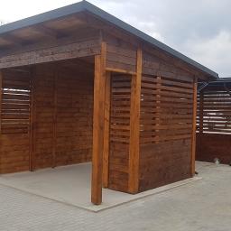 Usługi Remontowo Budowlane ROB-BUD Robert Mrozik - Dwie drewniane altany z poziomymi deskami, połączone z budynkiem z szarą elewacją, widok z zewnątrz na brukowany plac.