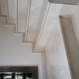 Marmurowe schody z widocznym fragmentem lustra w czarnej ramie, jasne wnętrze.