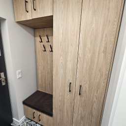 Flormeb - Komplet szaf i siedziska w przedpokoju, wykończone drewnopodobną okleiną z czarnymi uchwytami, na podłodze wzorzyste płytki.