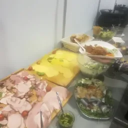 Bufet z różnorodnymi przekąskami: wędliny, sery, sałatki i sosy, przygotowany na przyjęcie.