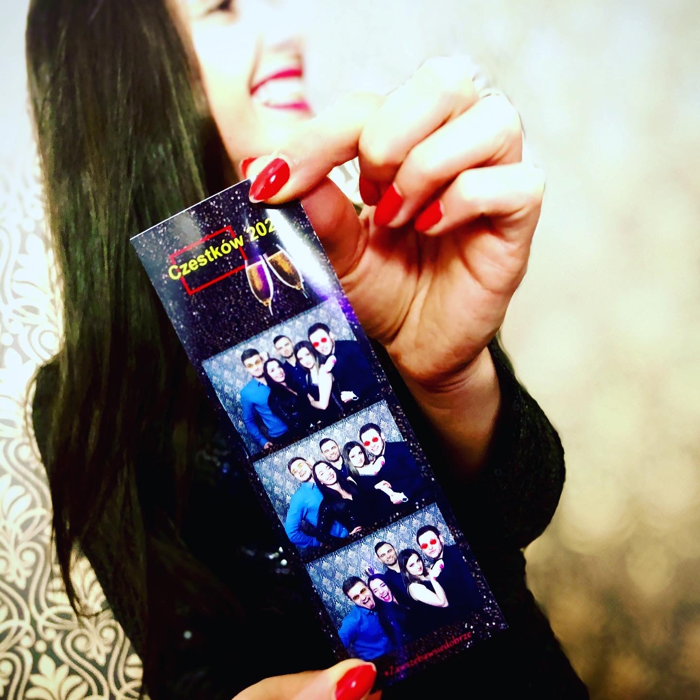 Kobieta trzyma pasek ze zdjęciami z fotobudki, na zdjęciach uśmiechnięte osoby w różnym ujęciu, na górze napis 'Cząstków 202'