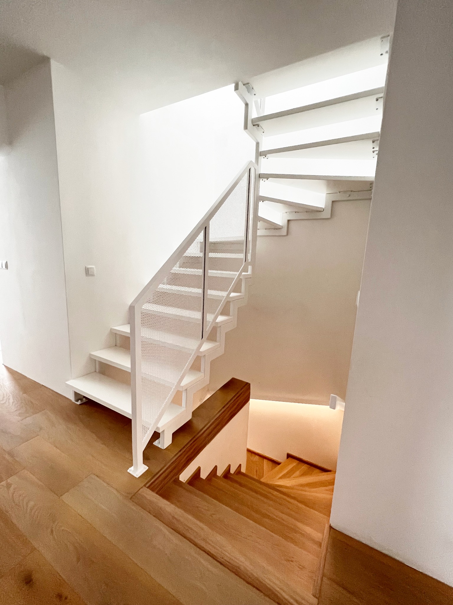 Białe schody samonośne z balustradą z siatki cięto ciągnionej