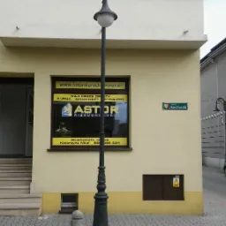 Fasada budynku agencji nieruchomości Astor z witryną zawierającą logo i ofertę kupna, sprzedaży i wynajmu, widoczna tabliczka z nazwą ulicy Kościuszki.