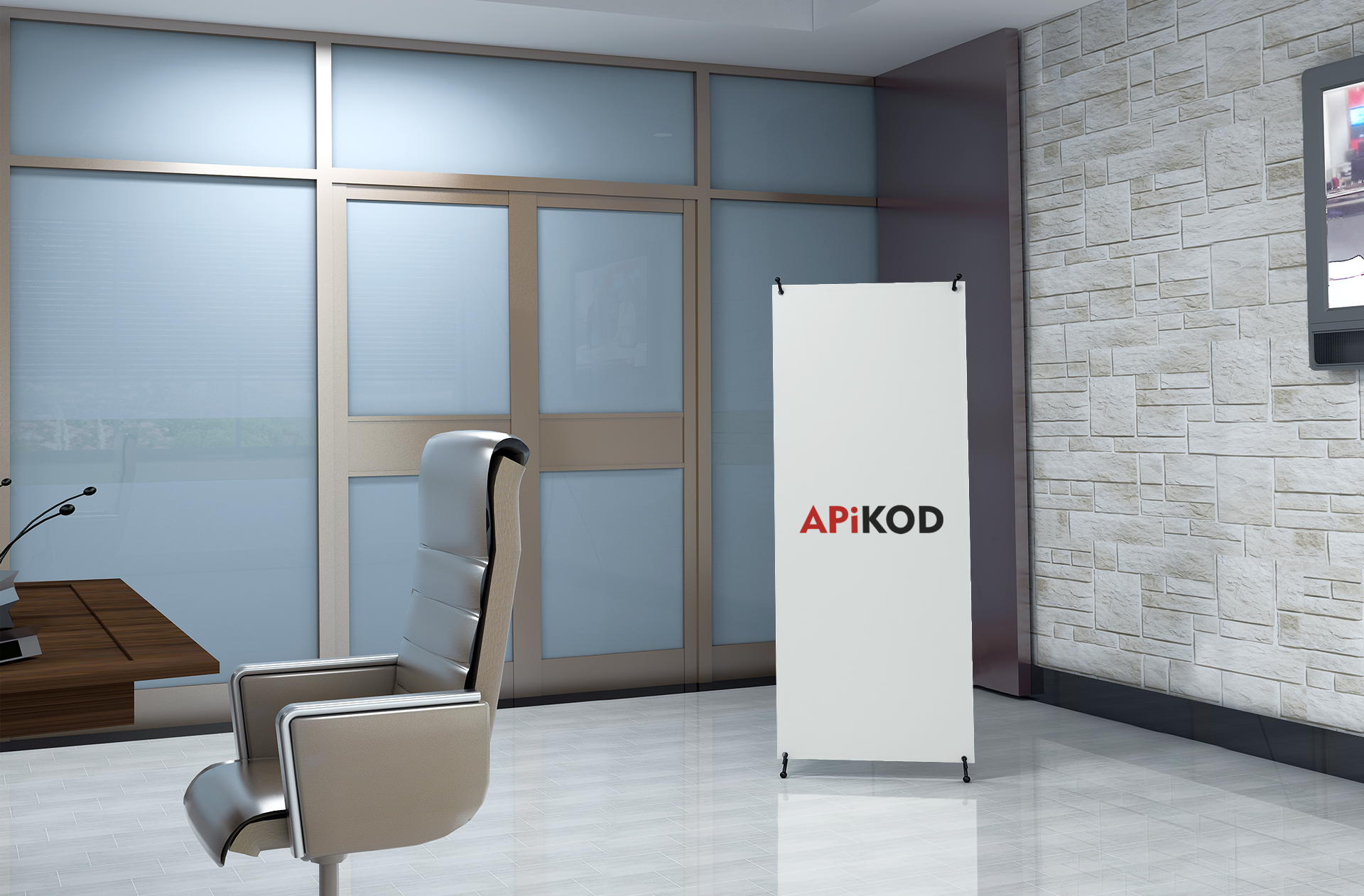 Wnętrze biura z nowoczesnym krzesłem, stołem z mikrofonami oraz banerem reklamowym z logo 'APIKOD' na tle ściany z cegły i dużego ekranu.
