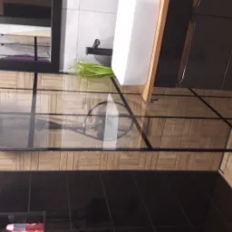 Nowoczesna kabina prysznicowa z czarnymi ramami, deszczownicą i baterią podtynkową, umywalka nablatowa z szafką w kolorze grafitowym, drewnopodobne płytki na ścianach i podłodze.