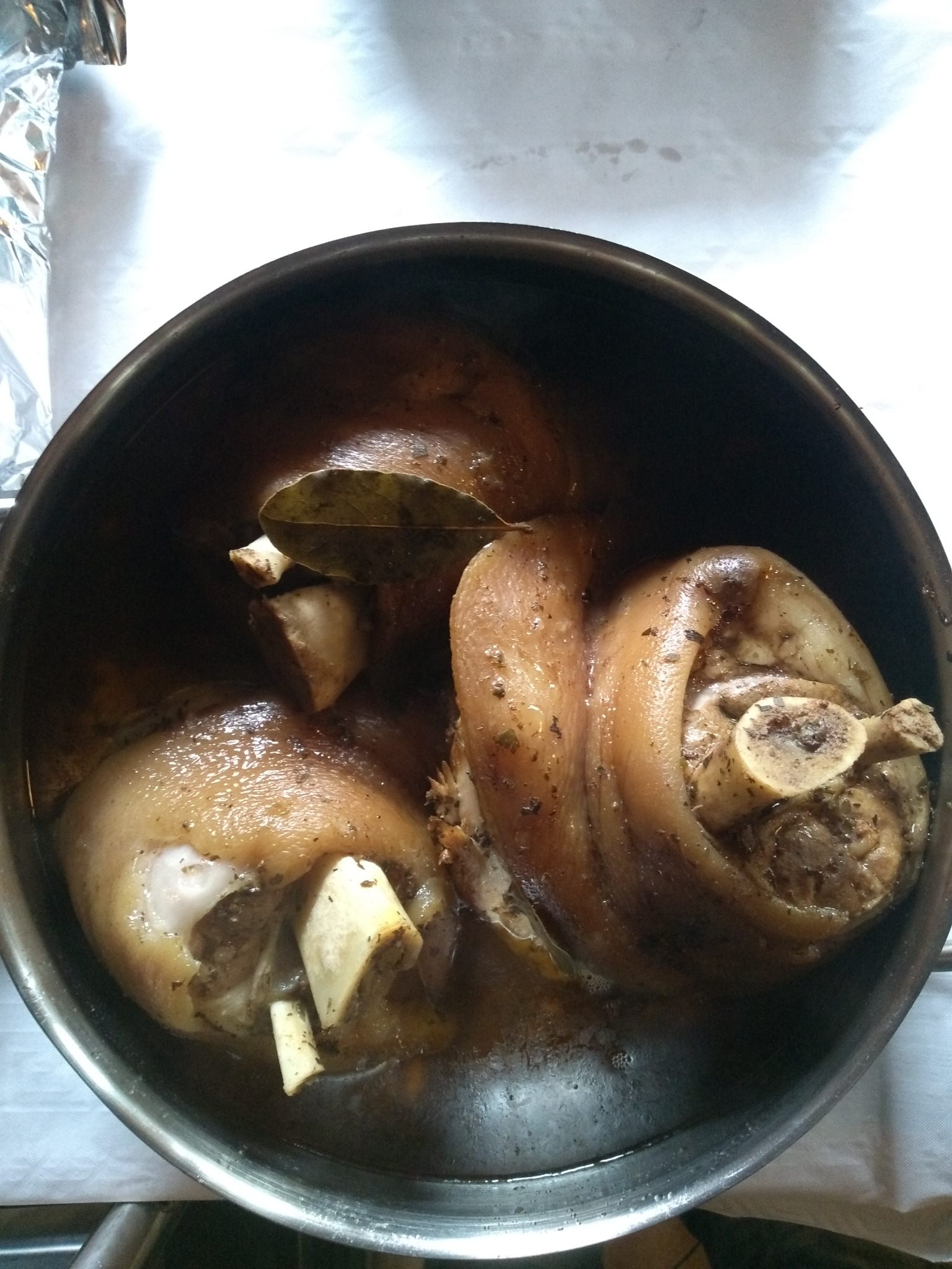 Gotowane golonki wieprzowe w metalowym garnku, z liściem laurowym, widoczne kości.