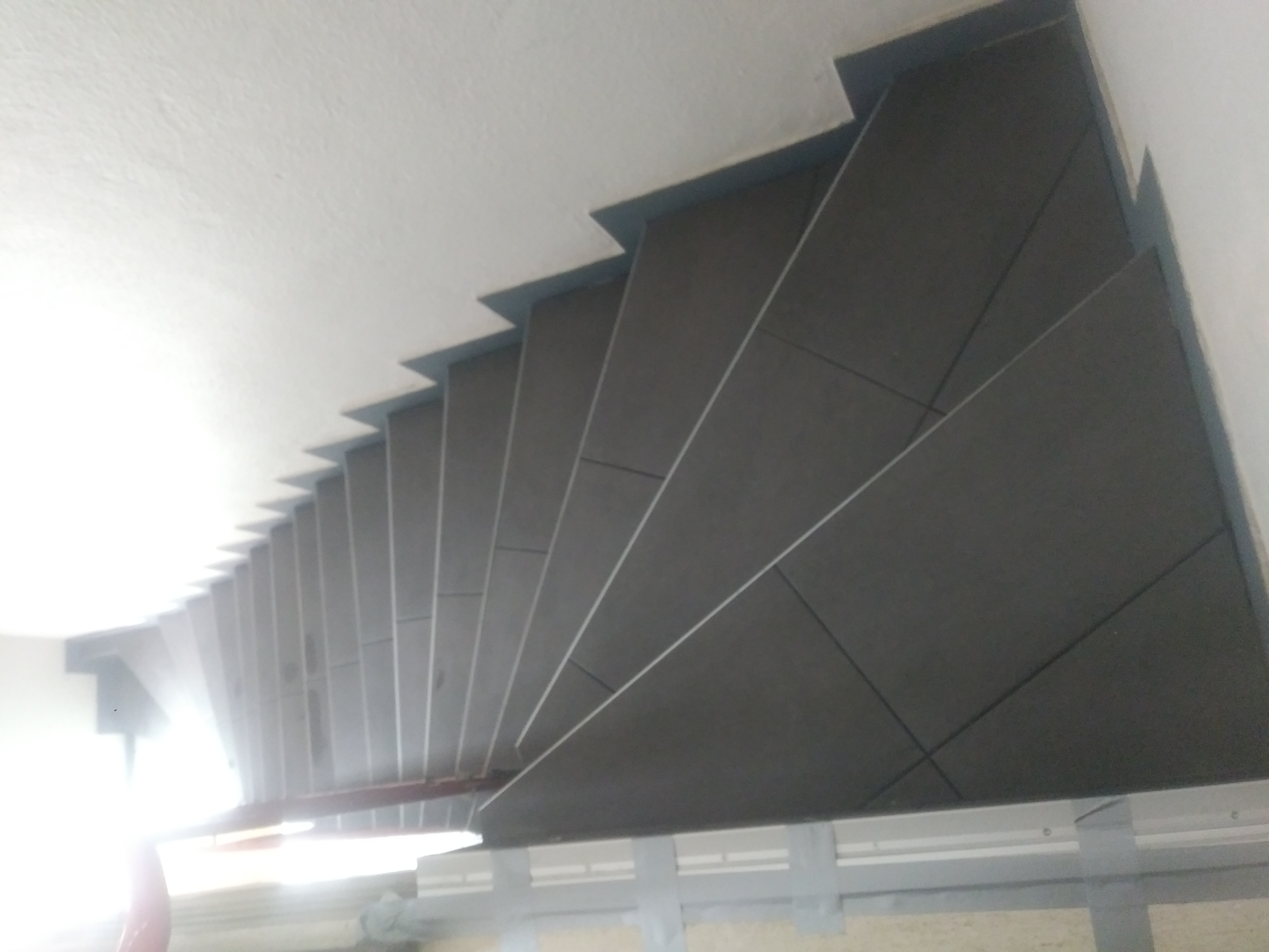 Wykończone schody wewnętrzne z ciemnoszarymi płytkami, widok z góry, z widocznym podświetleniem u dołu.