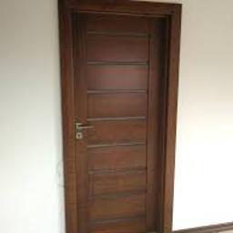 Usługi Monterskie Głodowski - Ciemnobrązowe drzwi wewnętrzne z poziomymi panelami i srebrną klamką, zamontowane w białej ścianie.