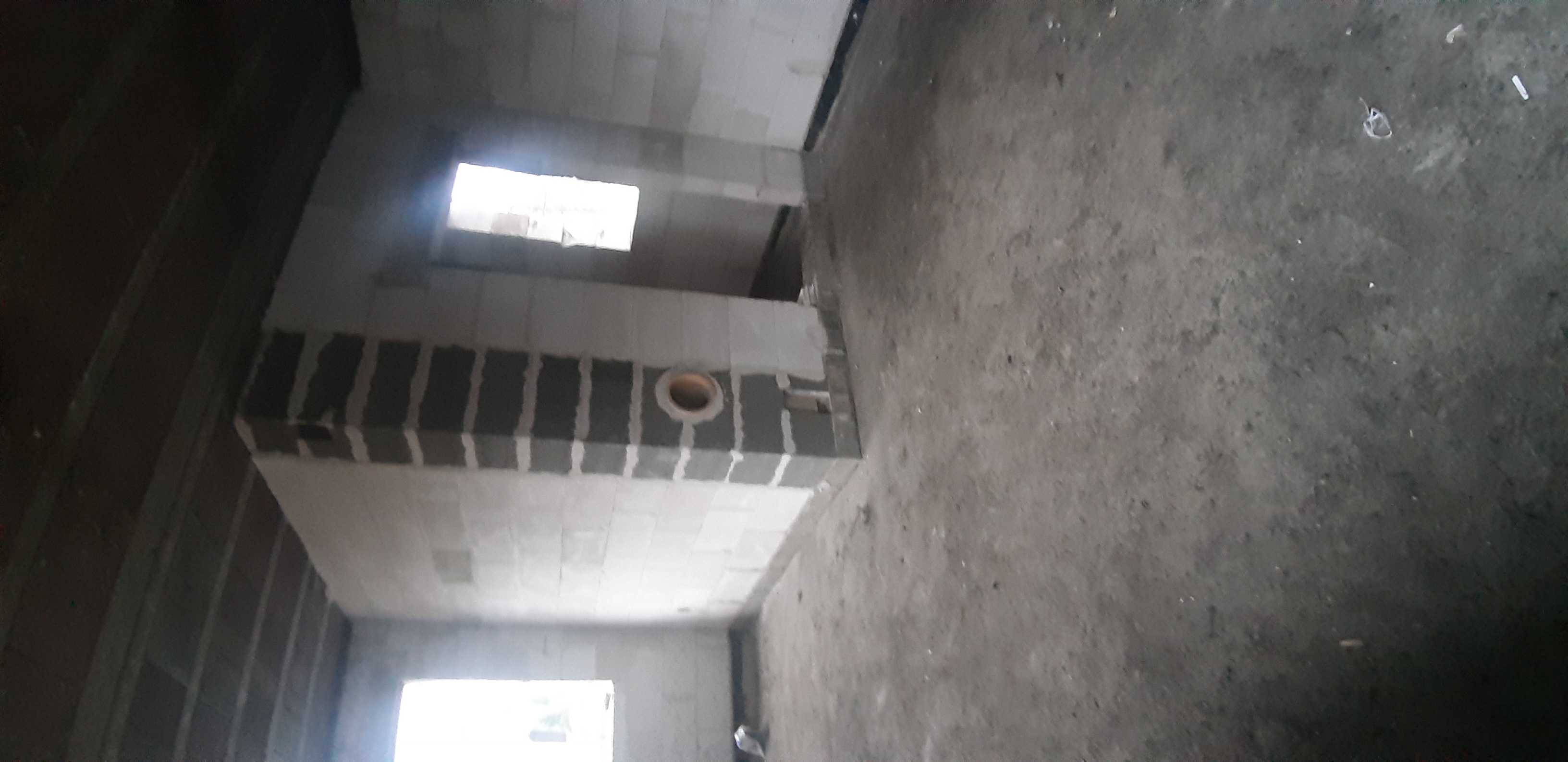 Surowy stan wnętrza z betonu komórkowego przed wykończeniem, widoczne otwory wentylacyjne i okna.