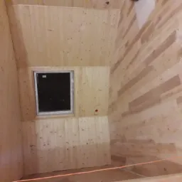 Poddasze wykończone boazerią z oknem, widoczne niedoskonałości montażu i ślady po pracach wykończeniowych.