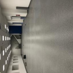 Floordeco - Korytarz biurowy z szarą wykładziną, widoczne schody i oświetlenie sufitowe