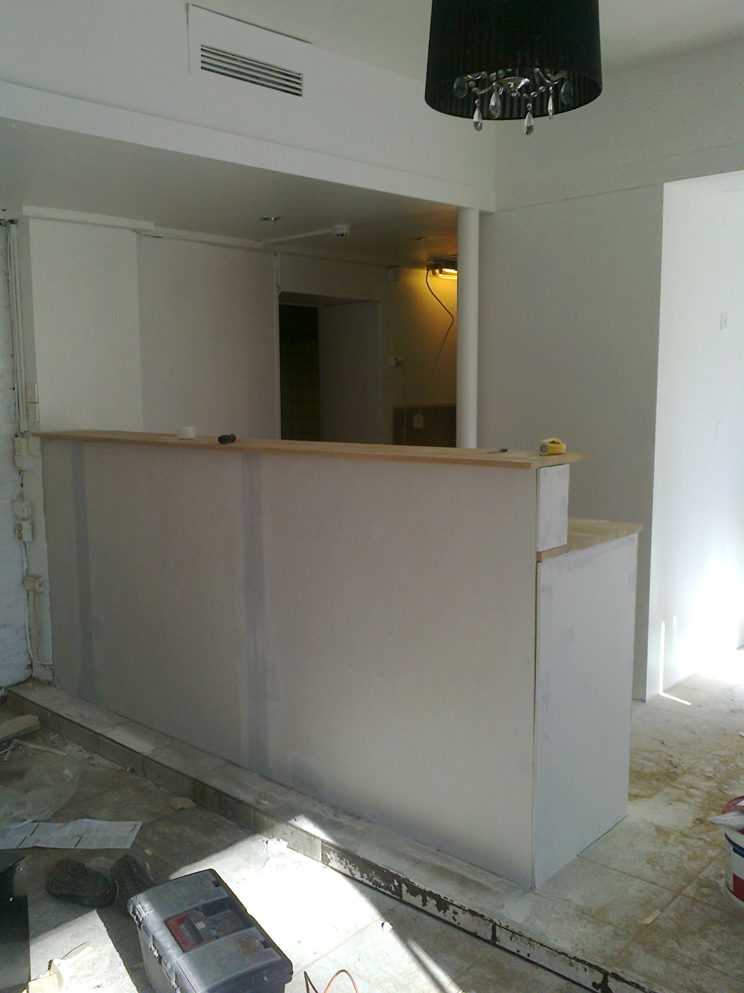 Konstrukcja baru z płyty karton gips, w trakcie szpachlowania, widoczna skrzynka z narzędziami i lampa sufitowa.