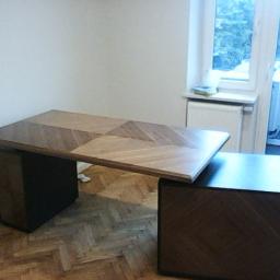 Rafał - Nowoczesne biurko z blatem w geometryczny wzór drewna, wsparte na dwóch szafkach nocnych w kolorze ciemnego brązu, na tle parkietu ułożonego w jodełkę.