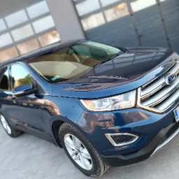 Błękitny Ford Edge zaparkowany przed garażem w Rzeszowie, widok z przodu z lekkiego ukosa.
