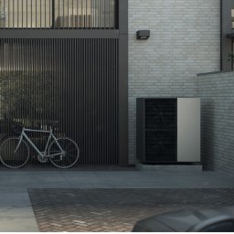 Connect Energy Spółka z Ograniczoną Odpowiedzialnością - Nowoczesny dom z pompą ciepła na zewnątrz, rower oparty o ścianę, minimalistyczny design, ceglana ściana w tle