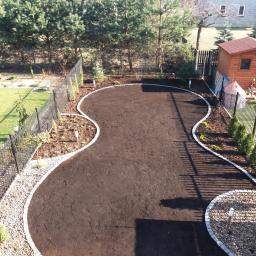 Tom-Kar - Przygotowany teren pod trawnik lub nasadzenia, obrzeża z jasnej kostki granitowej, widok z góry na posesję z metalowym ogrodzeniem i drewnianą altaną.